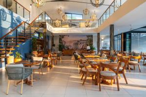 a restaurant with tables and chairs and a staircase at Waterfalls Lodge in Victoria Falls