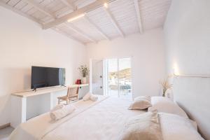 a white bedroom with a large bed and a tv at Drio Kythnos Suites in Dhriopís