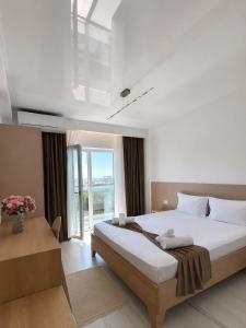 a bedroom with a large bed and a large window at Marevento Hotel in Costinesti