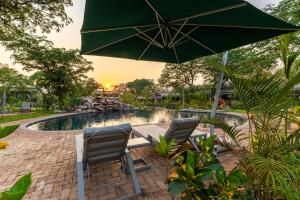 two chairs and an umbrella next to a pool at Waterfalls Lodge in Victoria Falls