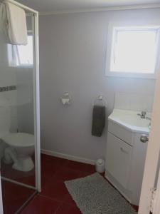 uma casa de banho com um lavatório, um WC e uma janela. em Atalaya em Waihi Beach