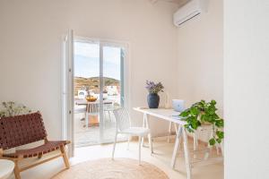 a white dining room with a table and chairs at Drio Kythnos Suites in Dhriopís
