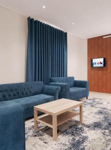 a living room with two blue couches and a coffee table at شاليهات المروان لبيوت العطلات - AL-Marwan for Holiday Homes in Ash Shafa