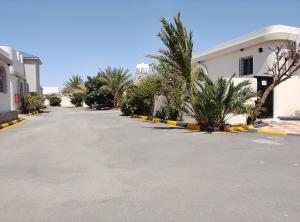 an empty parking lot with palm trees and a building at شاليهات المروان لبيوت العطلات - AL-Marwan for Holiday Homes in Ash Shafa