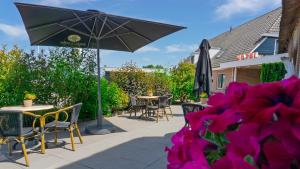 a patio with tables and chairs and an umbrella at Hotel de Harmonie in Giethoorn