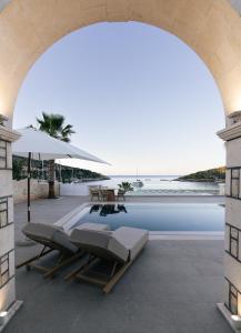 an archway over a pool with chairs and an umbrella at Alýria Sea Side Suites in Agios Nikolaos