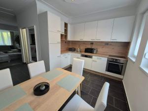 a kitchen with a wooden table and white cabinets at Green Terrace Residence in Zalaegerszeg