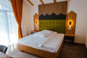 a bedroom with a large bed with a green headboard at Wolf Chalet - Moieciu de Sus in Moieciu de Sus +31 photos