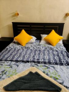 a bed with two yellow pillows and a blanket at Mount Homestay in Nedukandam