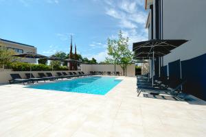 a swimming pool with chairs and umbrellas next to a building at Hotel Cabecinho in Anadia
