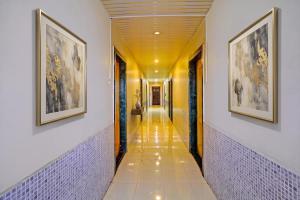 a hallway with two paintings on the walls and a hallwayngthngthngthngthngth at FabHotel Wagholi Inn in Pune