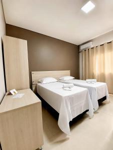 two beds in a hotel room with two tables at Kuri Hotel in Padre Bernardo