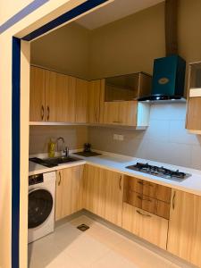 a kitchen with wooden cabinets and a washing machine at Private & Serene Golf View Apt Phase 7 in Rawalpindi