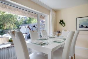a white dining room with a white table and white chairs at Henning in Keitum