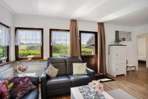 a living room with a leather couch and windows at Ferienhaus Bianca in Meschede