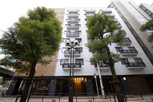 un bâtiment blanc avec des arbres devant lui dans l'établissement Hotel Cordia Osaka, à Osaka