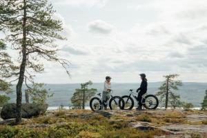 two people walking their bikes on a hill at Grand Arctic Resort in Överkalix