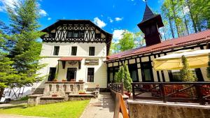 an old house with a black and white building at Stavilar Hotel - Charming Stay Just Steps Away from Peles Castle in Sinaia in Sinaia