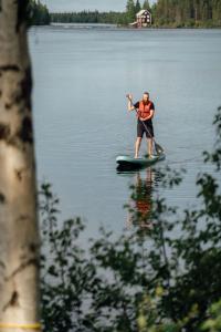 a man on a paddle board on a lake at Grand Arctic Resort in Överkalix