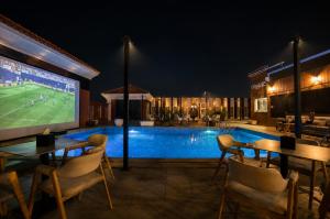 a pool with a tv and tables and a soccer game on a screen at Eliana Hotel in Al Khobar