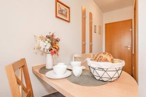 a table with a basket of bread and cups on it at Ostseeglück App Mittagsonne in Loddin +22 photos