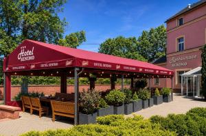 a restaurant with a red umbrella and tables and benches at Hotel Senimo in Olomouc