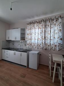 a kitchen with white cabinets and a table and a window at Sunset Bliss Apartments in Sarandë +14 photos