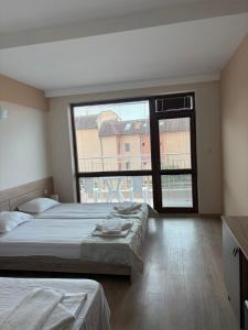 a bedroom with two beds and a large window at Cattleya in Nesebar