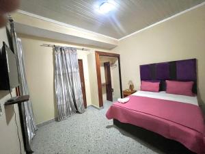 a bedroom with a bed with pink and purple pillows at Hotel Residencial Assamar in Pemba