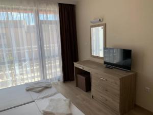 a bedroom with a television and a dresser with a mirror at Cattleya in Nesebar