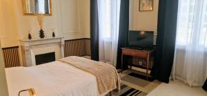 a bedroom with a bed and a fireplace and a television at Suite Millésime du Château - Proche Océan in Gaillan-en-Médoc +3 photos