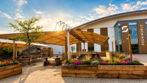 a building with a patio with benches and flowers at Alpine Hotel in Bispingen