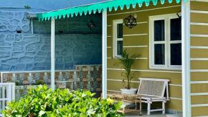 a yellow house with a bench on the porch at The Hills Boho in Mukteshwar +15 photos