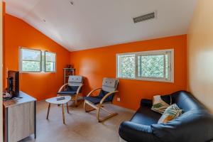 a living room with orange walls and a couch and chairs at Maison de Charme in Mimizan-Plage