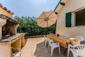 a patio with a table and chairs and an umbrella at Maison de Charme in Mimizan-Plage