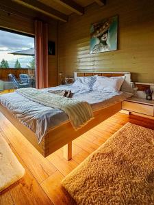 a large bed in a room with a wooden floor at Belis Chalet in Bălceşti