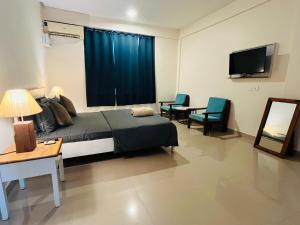a bedroom with a bed and a tv and chairs at Hotel 14 Pods Morjim in Morjim