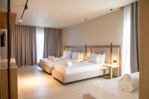 two beds in a hotel room with white furniture at South Inn Marina Hotel in Vlorë