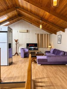 a living room with purple couches and a tv at Chalet Duplex N 6 avec piscine in Bouzareah