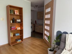 a living room with a book shelf next to a kitchen at Przytulne mieszkanie blisko morza in Gdańsk