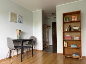 a dining room with a table and chairs and a book shelf at Przytulne mieszkanie blisko morza in Gdańsk +3 photos