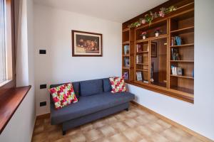a living room with a blue couch and a book shelf at Meridiana Gemona in Taboga