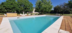 a swimming pool with chairs and a house at Suite Millésime du Château - Proche Océan in Gaillan-en-Médoc