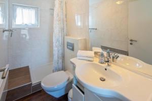 a bathroom with a sink and a toilet and a shower at Ferienhaus Mackeriege in Norden +18 photos