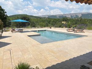 a swimming pool with a table and a blue umbrella at Maison Time-out in Villevieille +18 photos