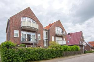 a red brick house with balconies on a street at Exklusive Ferienwohnung Sonnenplatz 30 in Norddeich