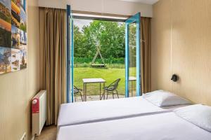 a bedroom with a bed and a sliding glass door at Stayokay Hostel Texel in Den Burg +43 photos