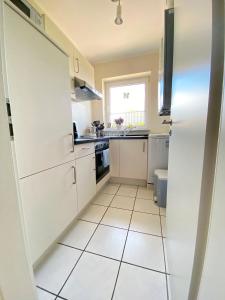 a kitchen with white cabinets and a tiled floor at Ferienwohnung Marianne 26835 Neukamperfehn in Neukamperfehn