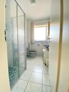 a bathroom with a glass shower and a toilet at Ferienwohnung Marianne 26835 Neukamperfehn in Neukamperfehn +16 photos