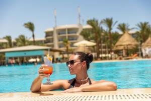 a woman in a swimming pool holding a drink at Siva Grand Beach in Hurghada